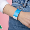 A woman wearing a white shirt and a plain neon blue wristband.