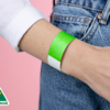 A person wearing a plain neon green wristband on their wrist.