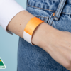 A close-up of a person wearing a plain neon orange wristband.