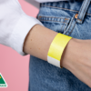 A person wearing a plain neon yellow Tyvek wristband and a white shirt