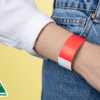 A woman wearing a red Tyvek wristband around her wrist.