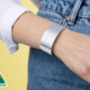 A close-up of a person wearing a plain silver Tyvek wristband.