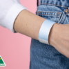 A close-up of a person wearing a plain sky blue Tyvek wristband.